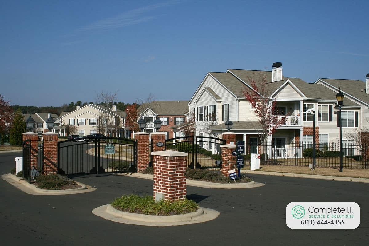 Gated community entrance with brick pillars and black swing gates