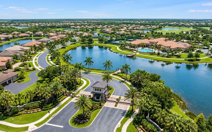 Aerial view of a Florida gated community with a gatehouse, winding entry road, clubhouse, and lakes