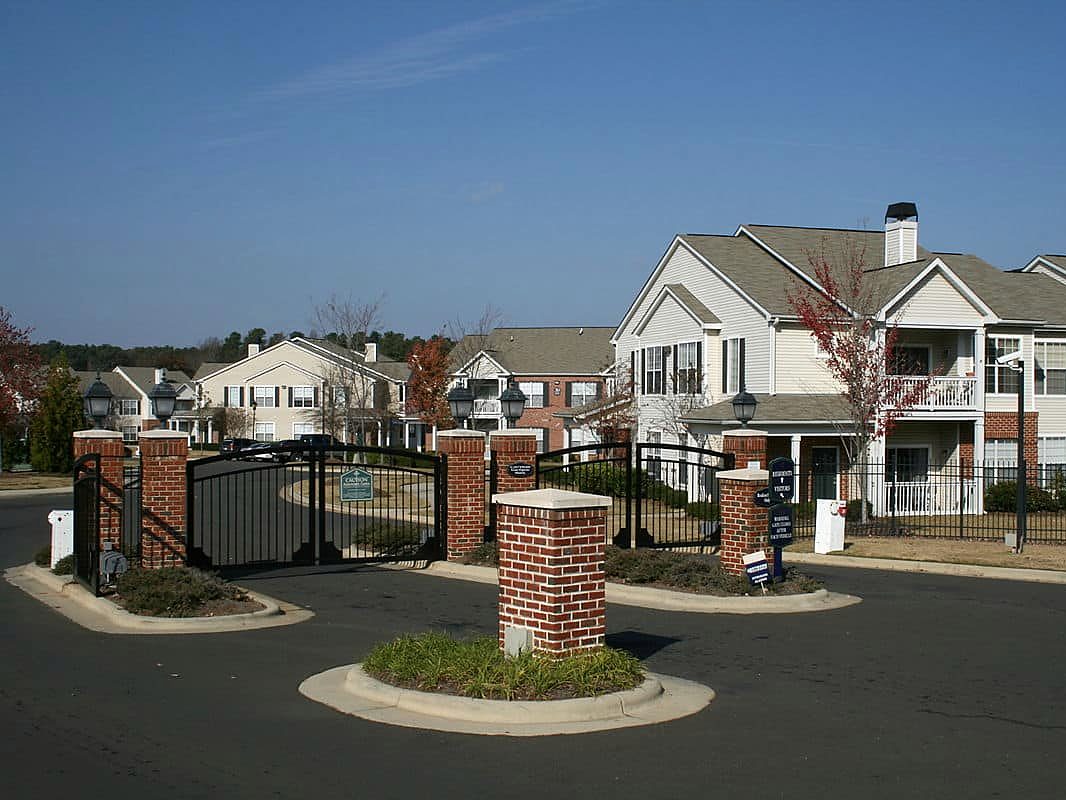 Gated community entrance with brick pillars and black swing gates